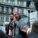 Christopher Wylie at outdoors protest speaking into megaphone