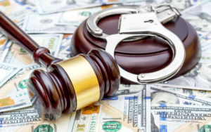 Wooden gavel and handcuffs on top of U.S. currency