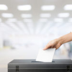 Hand dropping paper ballot into sealed black box