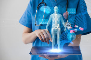 Person in scrubs holding computer tablet projecting medical data