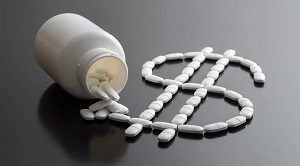 pill container spilled over with pills in the form of a dollar sign