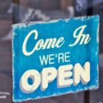 Business sign saying "Come In We're Open" in white on blue background