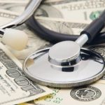 stethoscope on top of hundred dollar bills scattered around