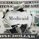 dollar bill with Medicaid text ripped through