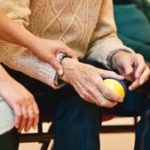 Woman holding elderly person's wrist
