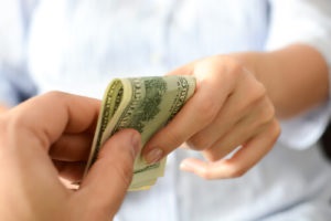 Person Handing Hundred Dollar Bill to Another Person
